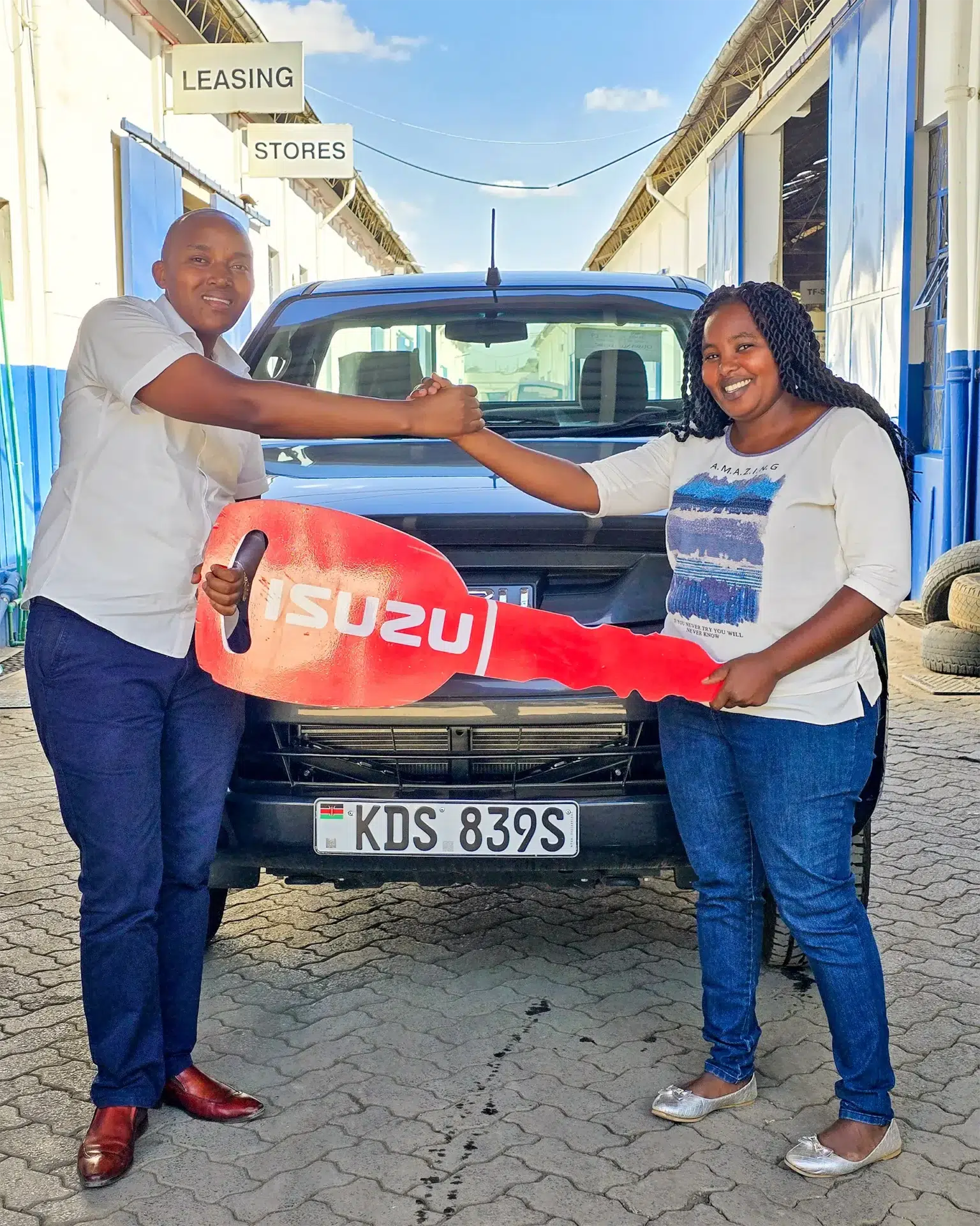 Beth Njeri Waithaka receiving her brand-new Isuzu Dmax 4x4 Single Cab BLUEPOWER from Wang'ombe, a top Isuzu sales representative in Kenya, during the official handover ceremony.