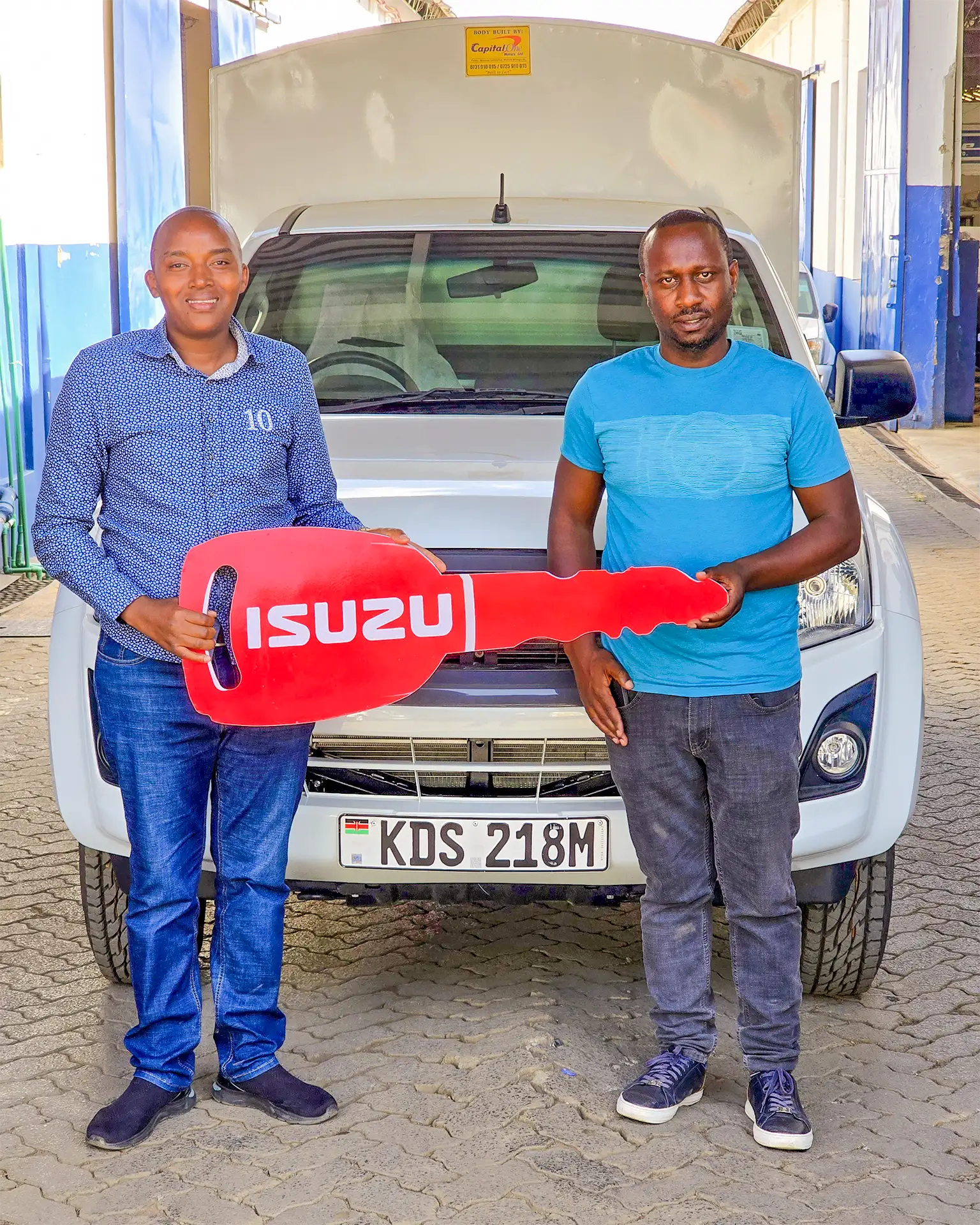 A representative from Danshi Enterprises Ltd receiving their brand-new Isuzu Dmax Single Cab Pick-up from Wang'ombe, a top Isuzu sales representative in Kenya, during the handover ceremony.