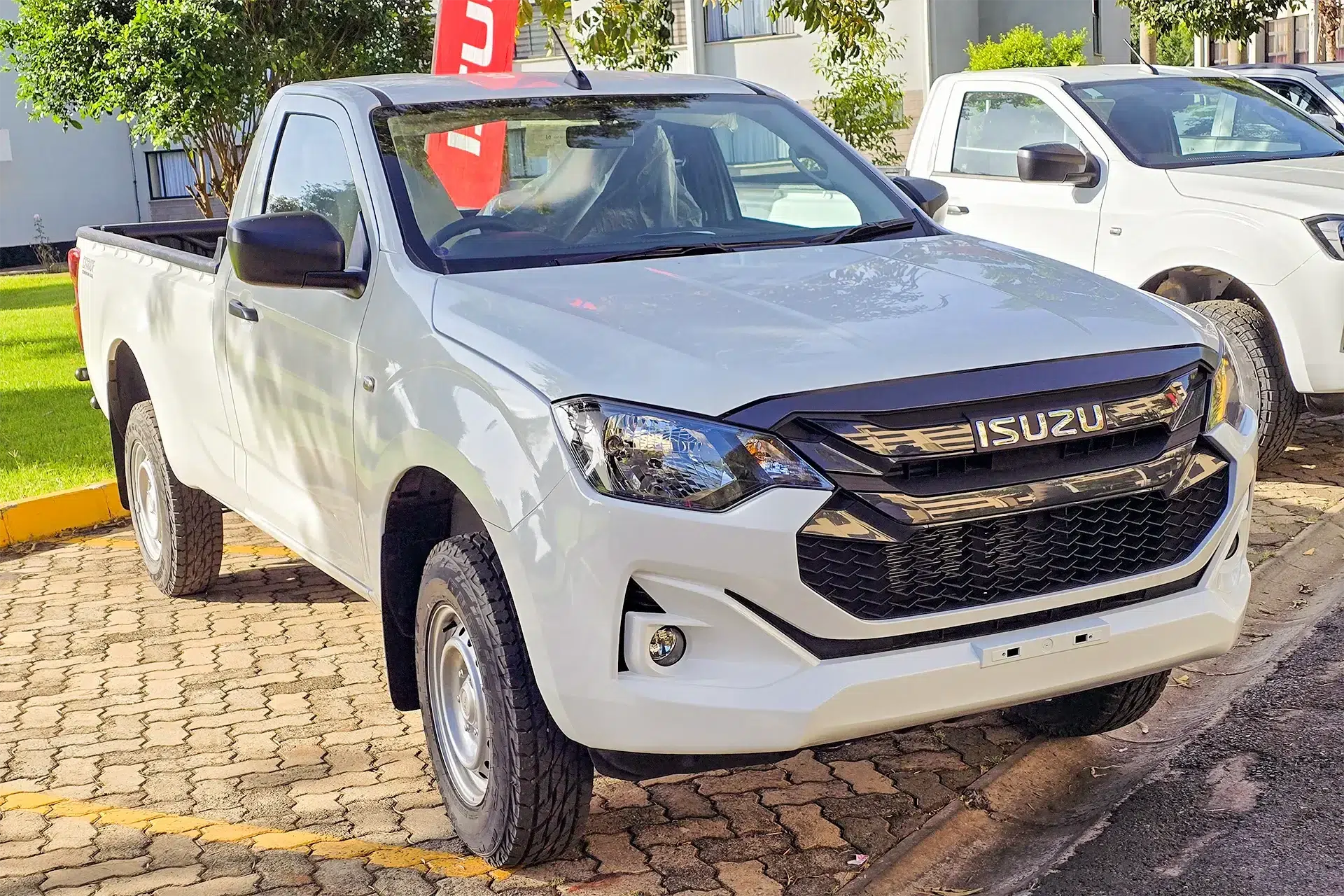 Front three-quarter view of a new white Isuzu D-Max 4x2 single cab pickup, showcasing its modern grille and headlights, available at Wangombe Truck Dealer in Kenya.