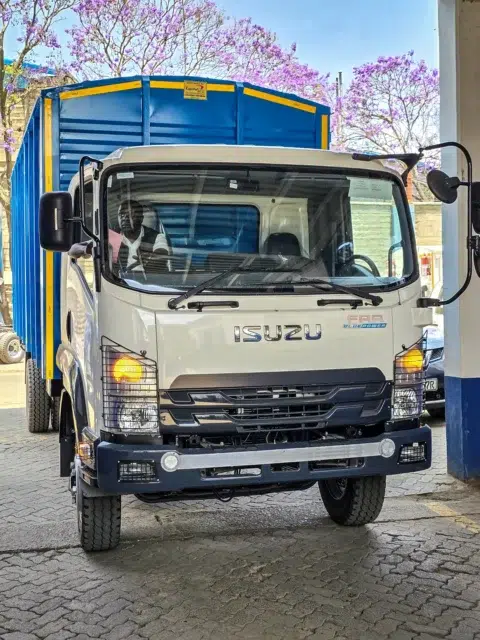 Front view of a new white Isuzu FRR 90 Bluepower truck with a custom blue cargo body.